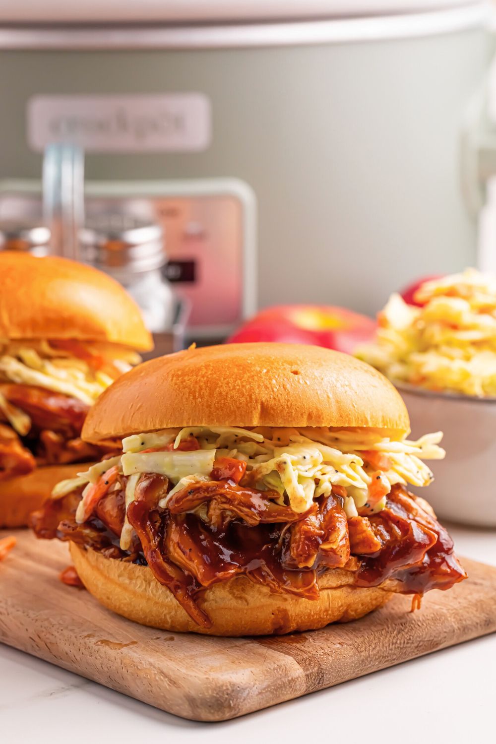 Crockpot Apple Butter BBQ Pulled Chicken sandwiches on table with a bowl of chips to the side 