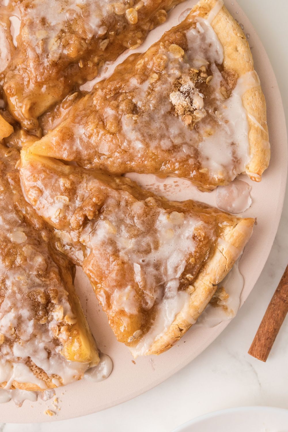 Apple Pie Pizza spread out on tray with some cinnamon sticks around table 