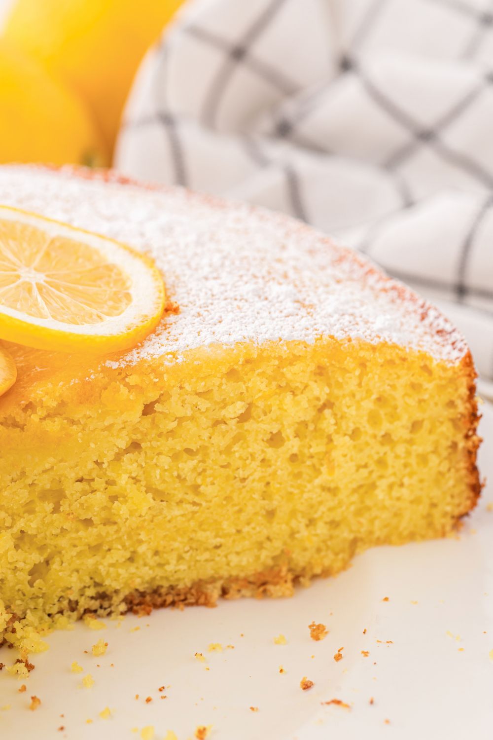 Italian Lemon Ricotta Cake sliced and placed on table with sliced lemon on top of cake 