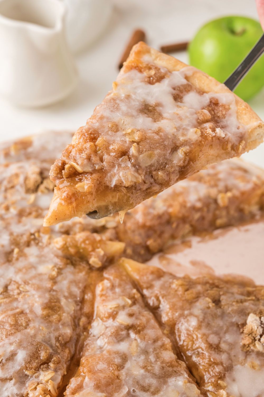 Apple Pie Pizza on table with one slice being lifted up off table 