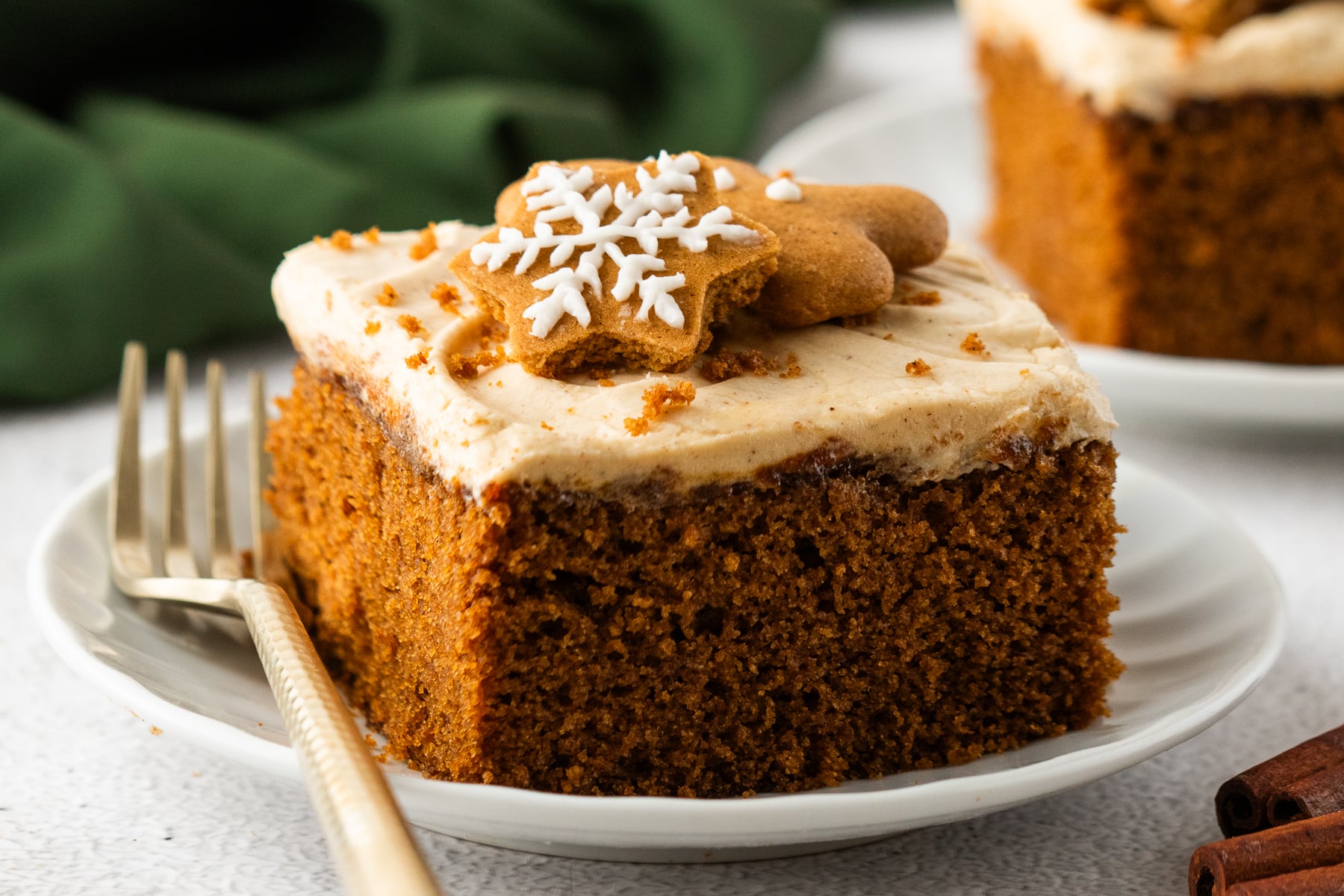 slices of Gingerbread Cake with Cream Cheese Frosting on white plates with a gold fork next to the slice 