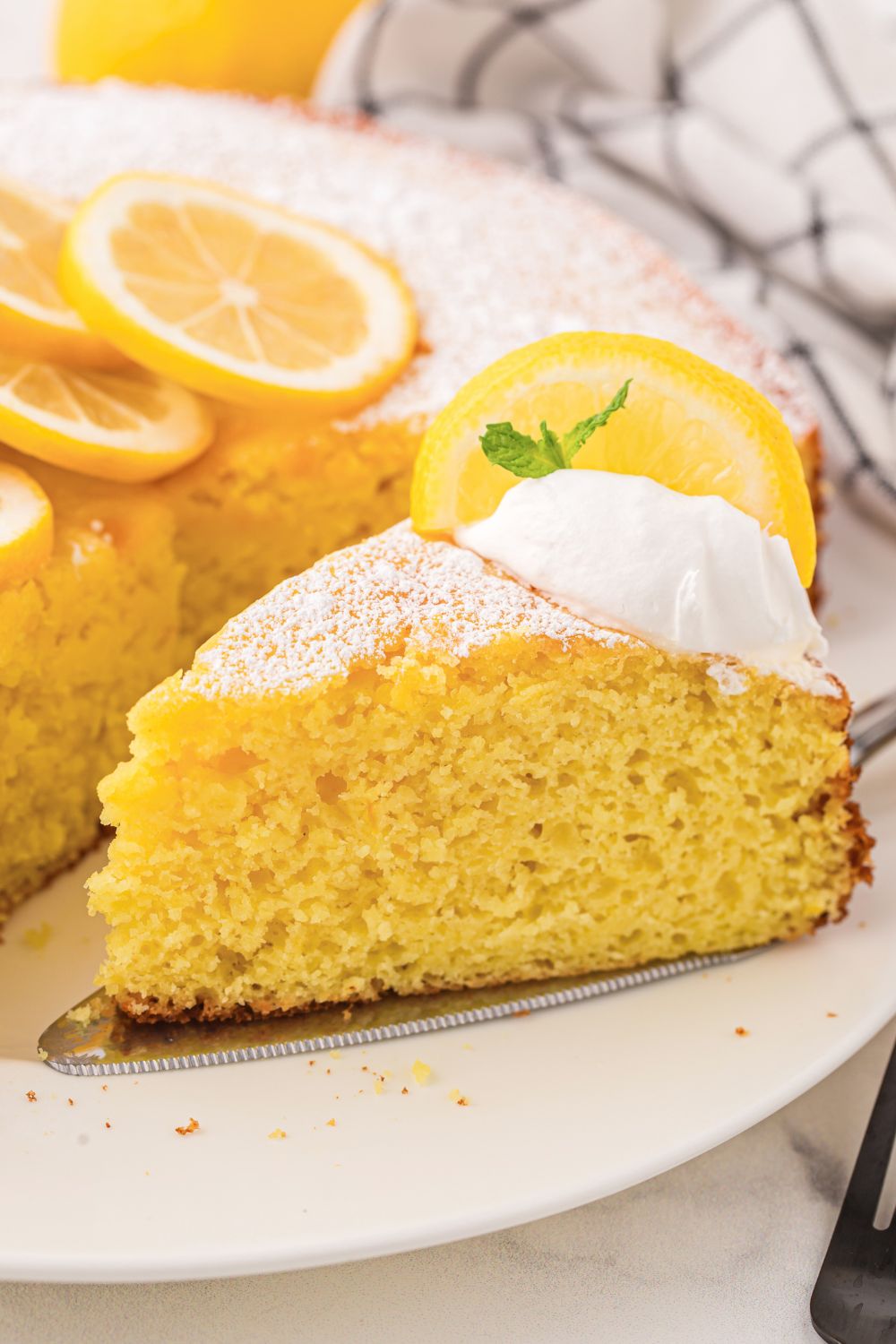 Italian Lemon Ricotta Cake on plate with a slice taken out of it 