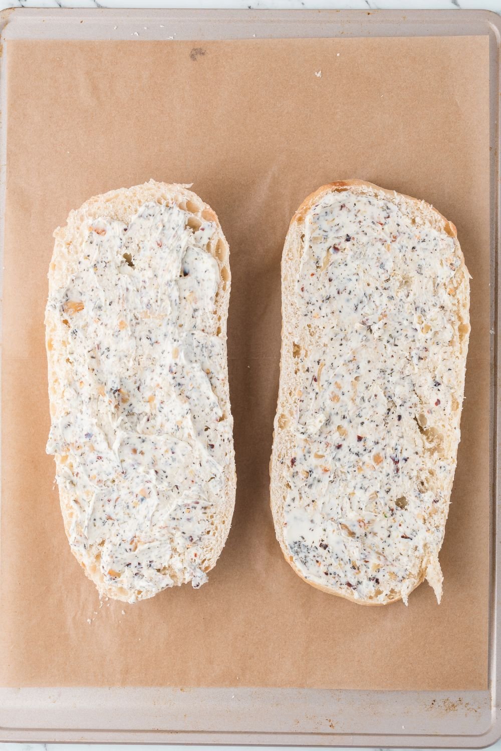 bread slathered with a garlic butter spread sitting on baking tray