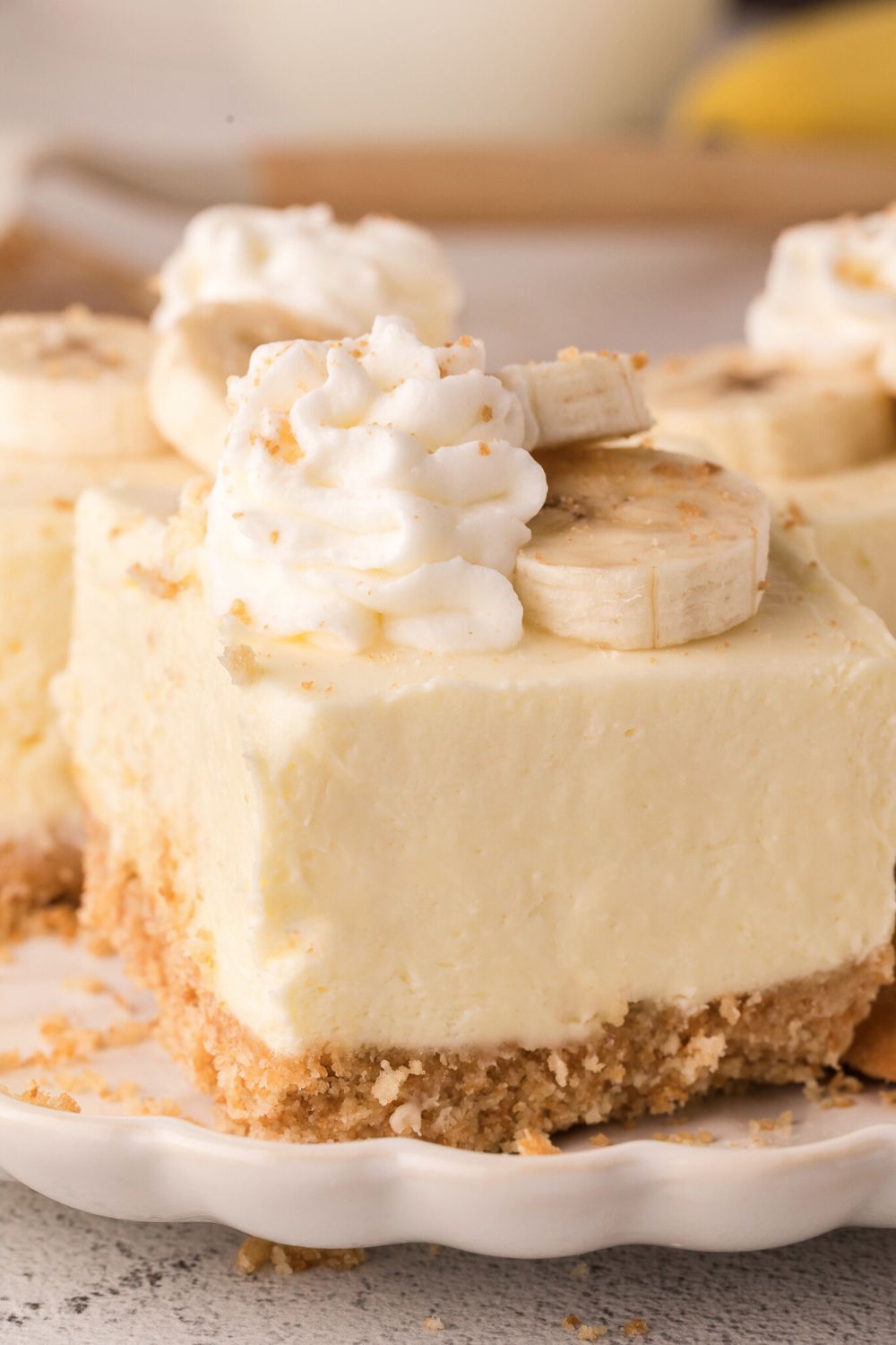 No Bake Banana Pudding Cheesecake Bars sliced and placed on table with crushed cookies around table 