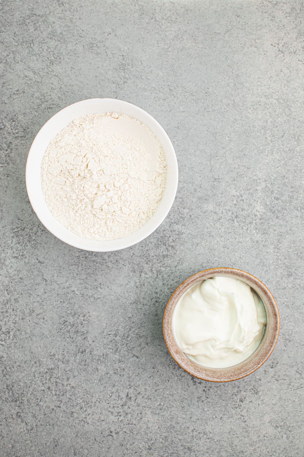 flour and Greek yogurt in bowls on table for making 2 Ingredient Dinner Rolls