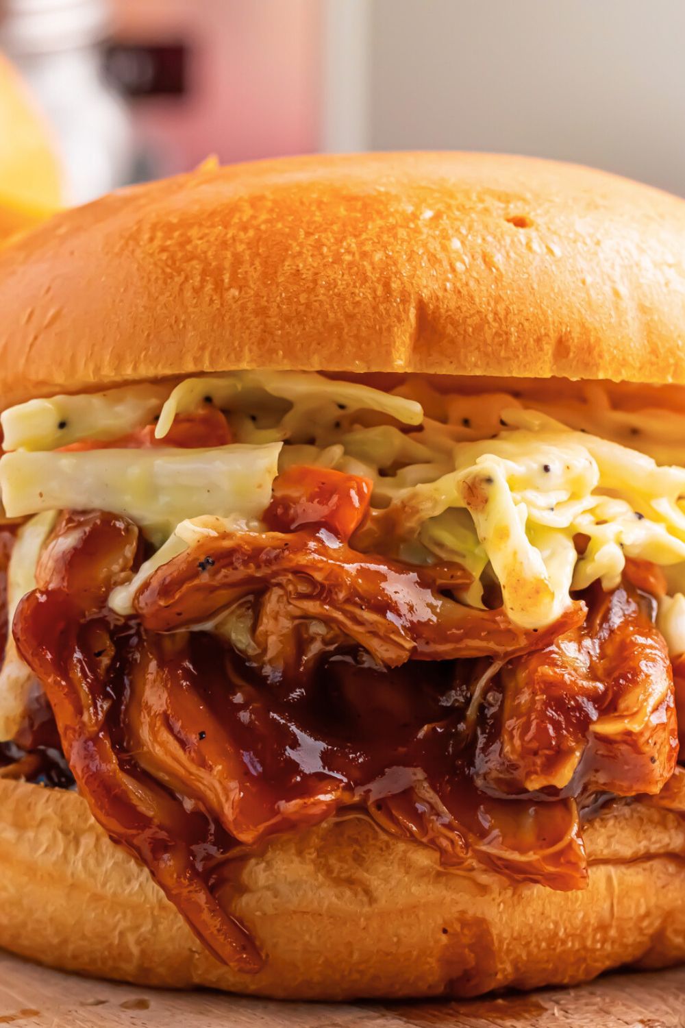 Crockpot Apple Butter BBQ Pulled Chicken sandwich on table with some coleslaw on top of meat 