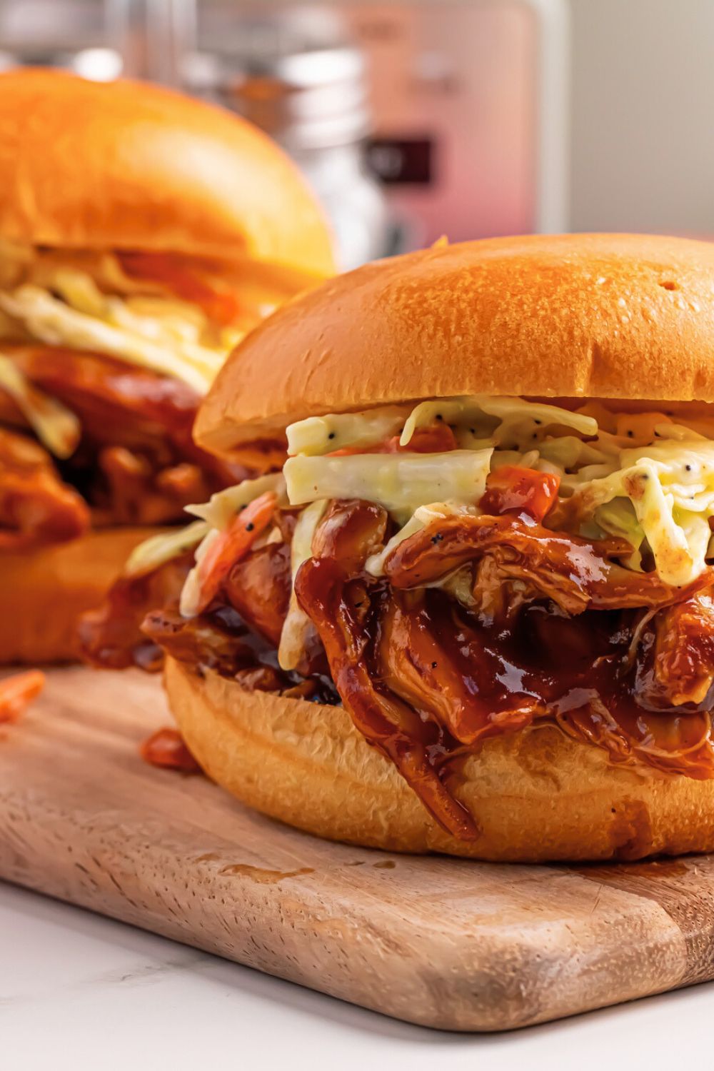 Crockpot Apple Butter BBQ Pulled Chicken sandwiches with cutting board to side