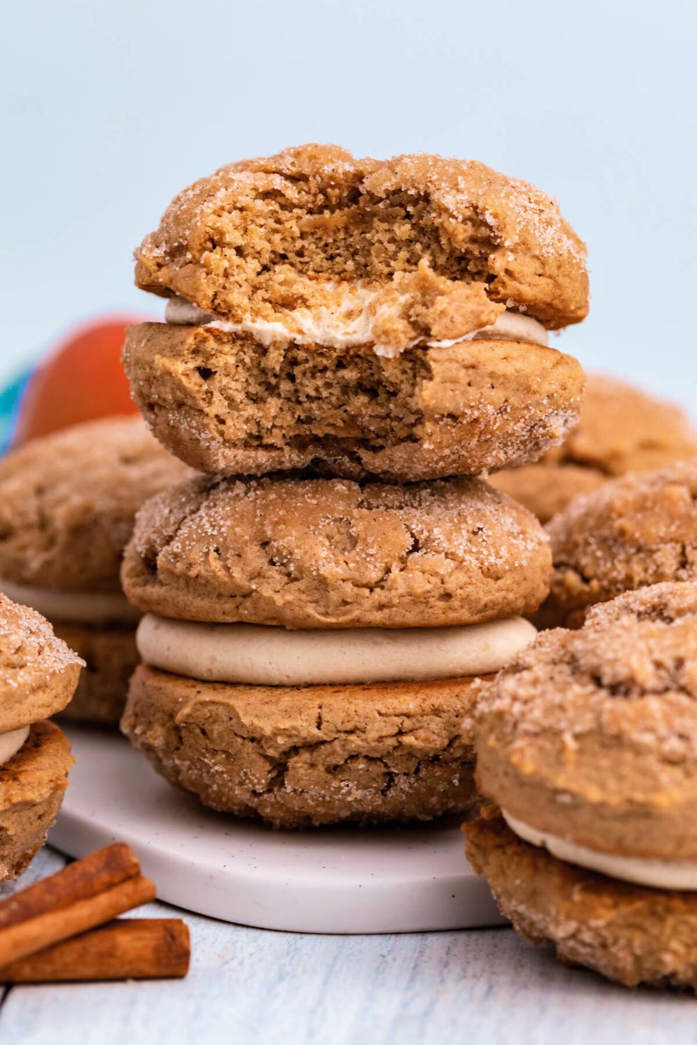 Apple Cider Whoopie Pies stacked on a plate with one with a bite taken out of it 