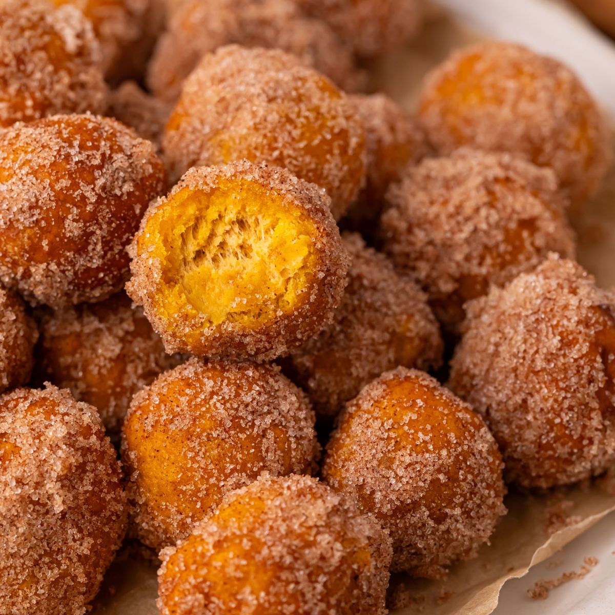2 Ingredient Pumpkin Pie Donut Holes on table with a bite taken out of one of the rolls