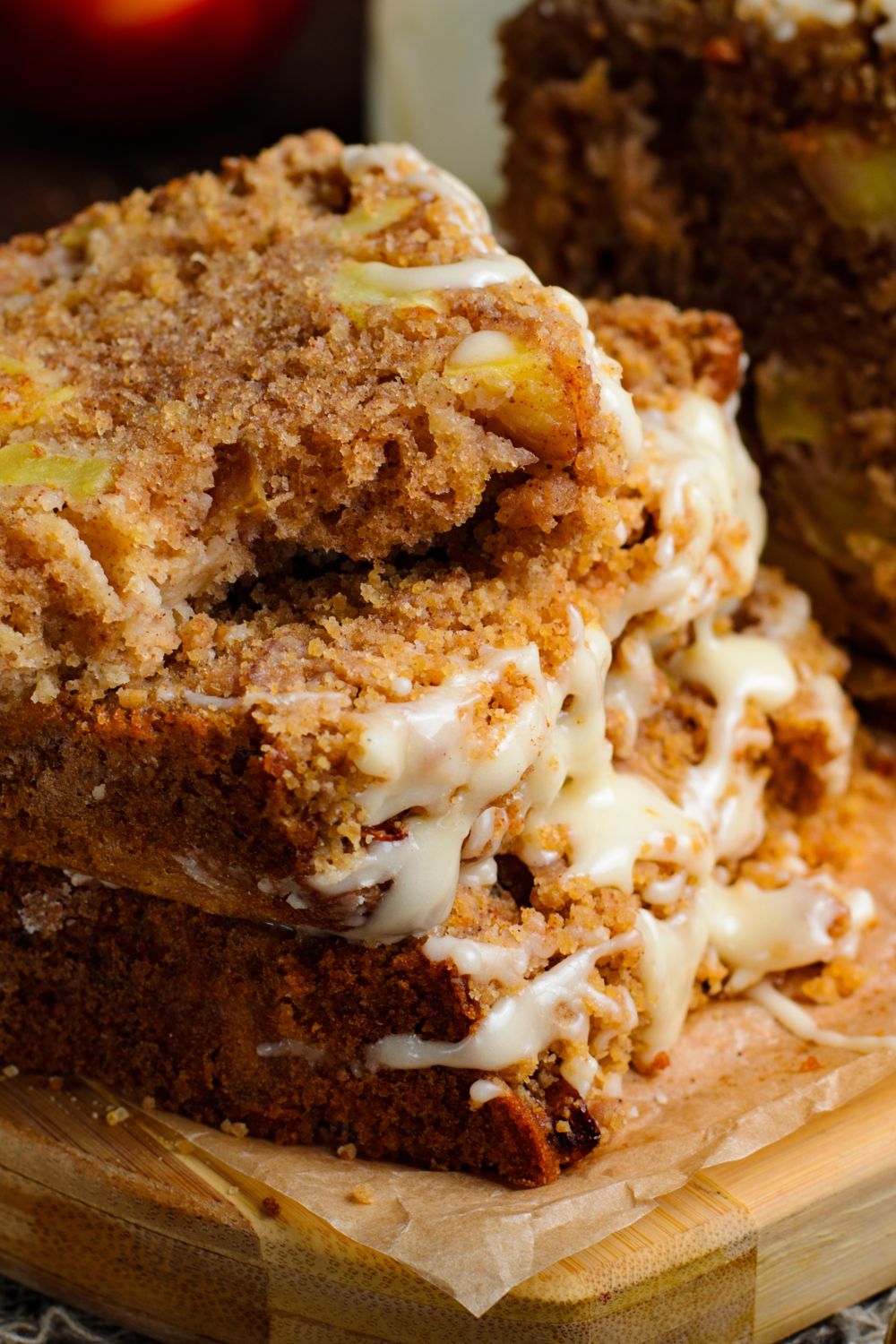 a few slices of Apple Cinnamon Loaf Cake stacked on top of one another with a few bites taken out of the top loaf sitting on a wooden cutting board 
