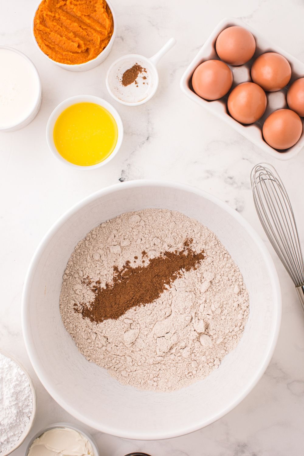 dry ingredients for making Pumpkin Bundt Cake in a white bowl on a marble counter