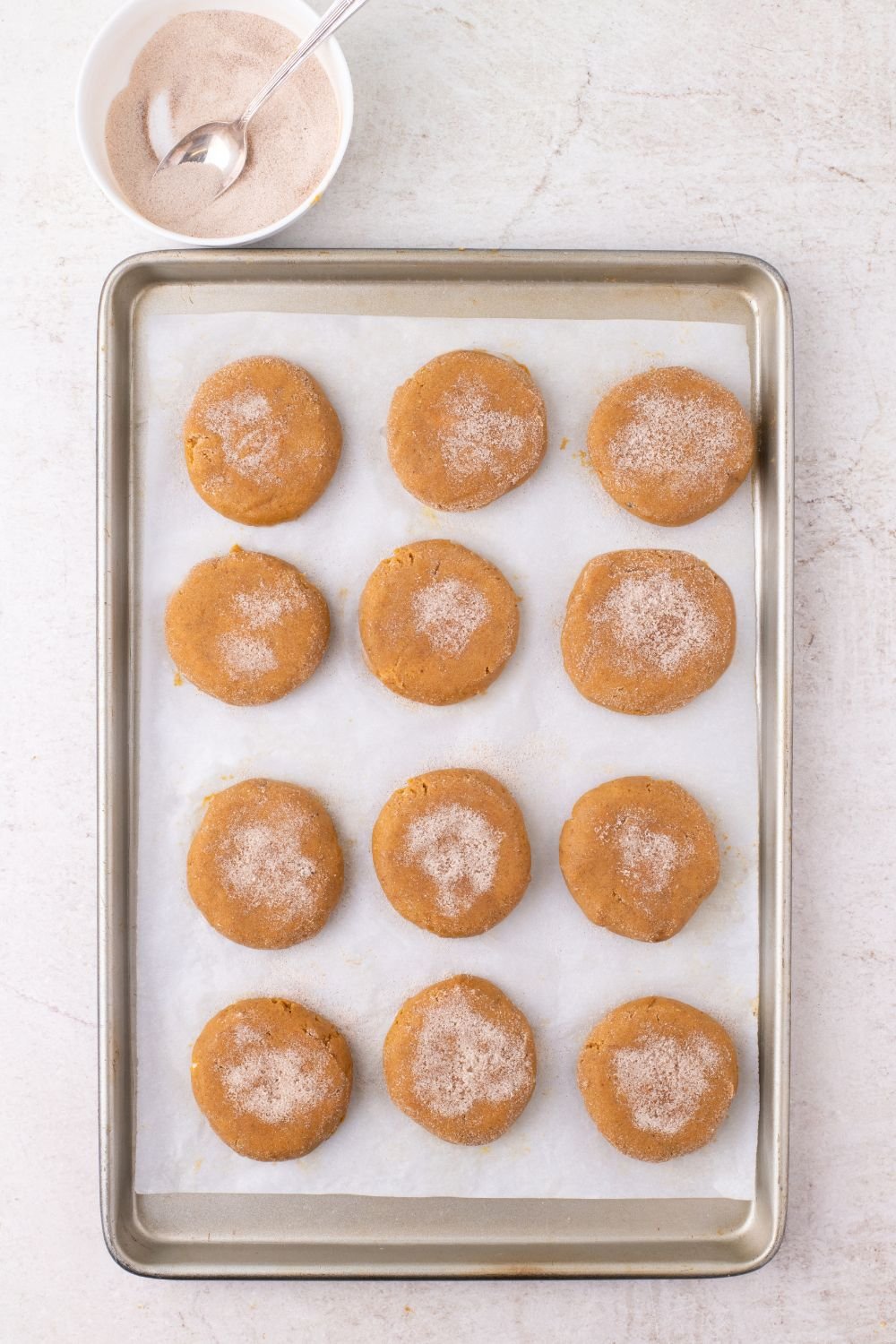 cinnamon sugar coated pumpkin cheesecake stuffed cookies on a baking tray 