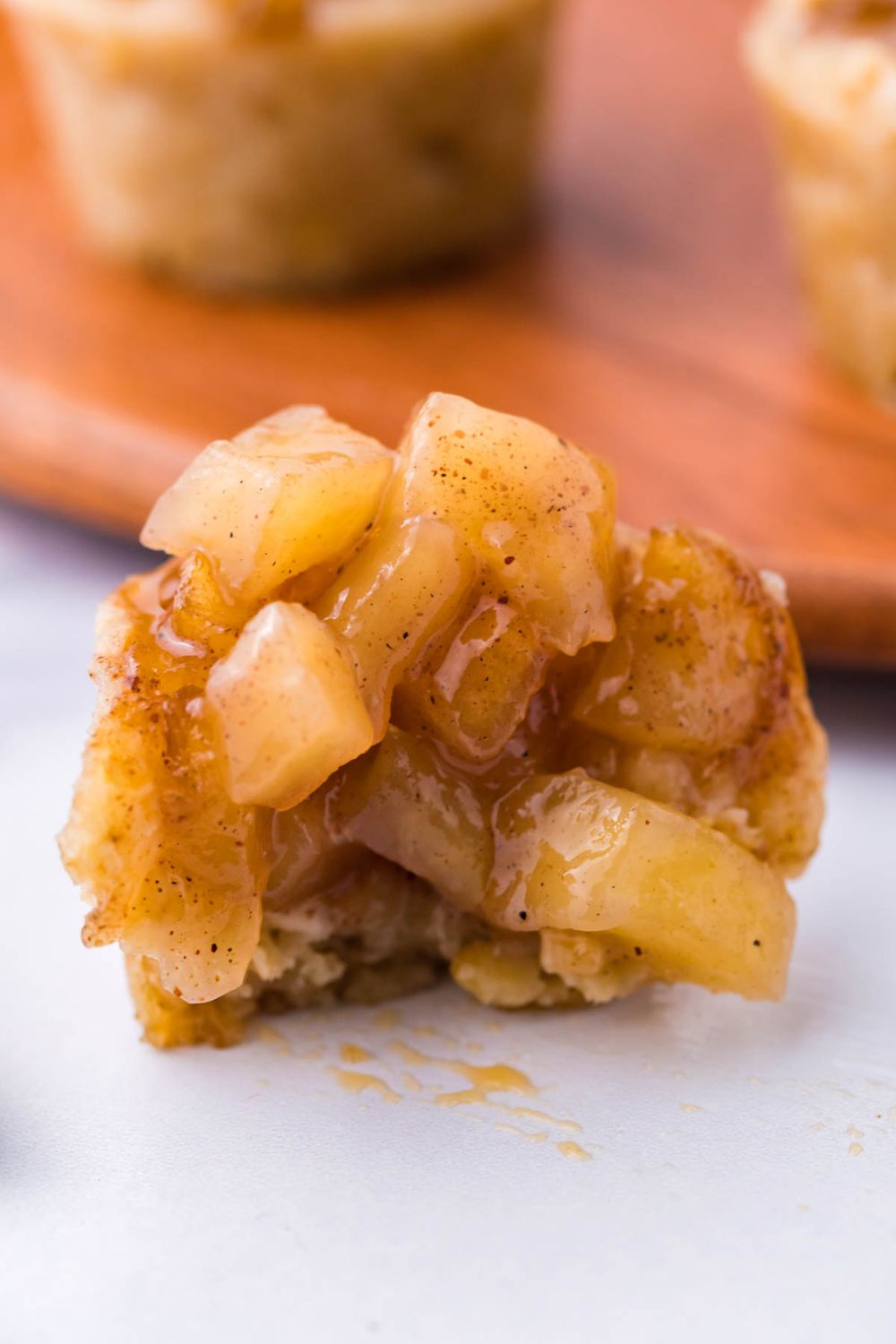 bite taken out of a mini apple crisp bite cup, with a bunch of the apple filling on top 