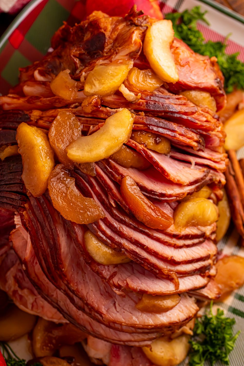 fully cooked Slow Cooker Apple Glazed Ham on a platter garnished with greens and cinnamon apples on top of ham 
