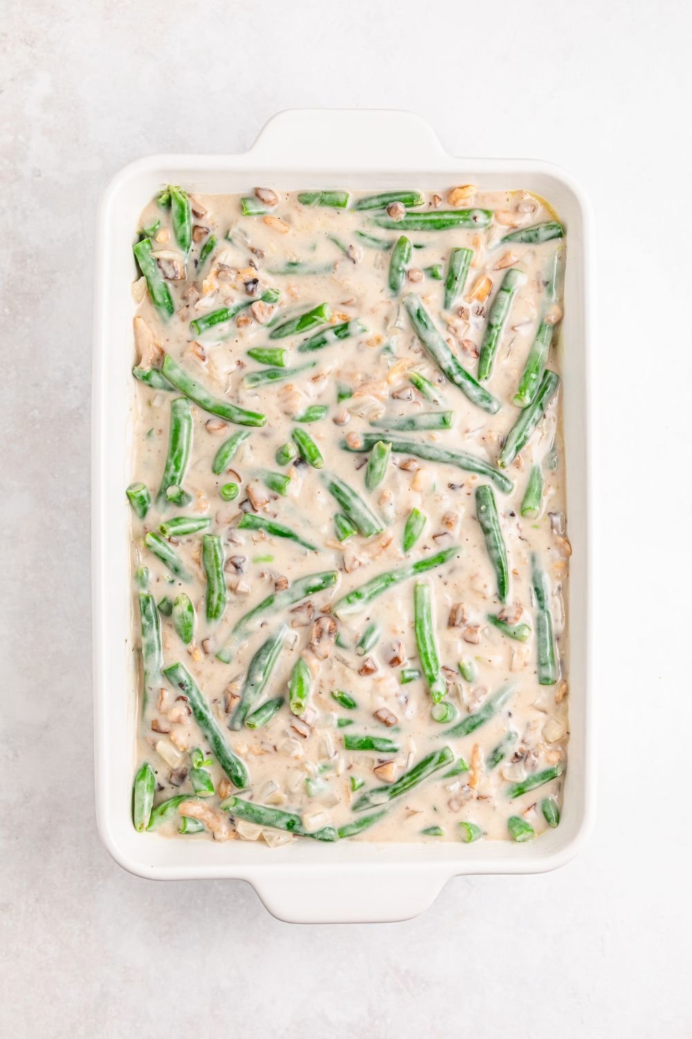 the mixture for Green Bean Casserole in a casserole dish with the green beans and the sauce 