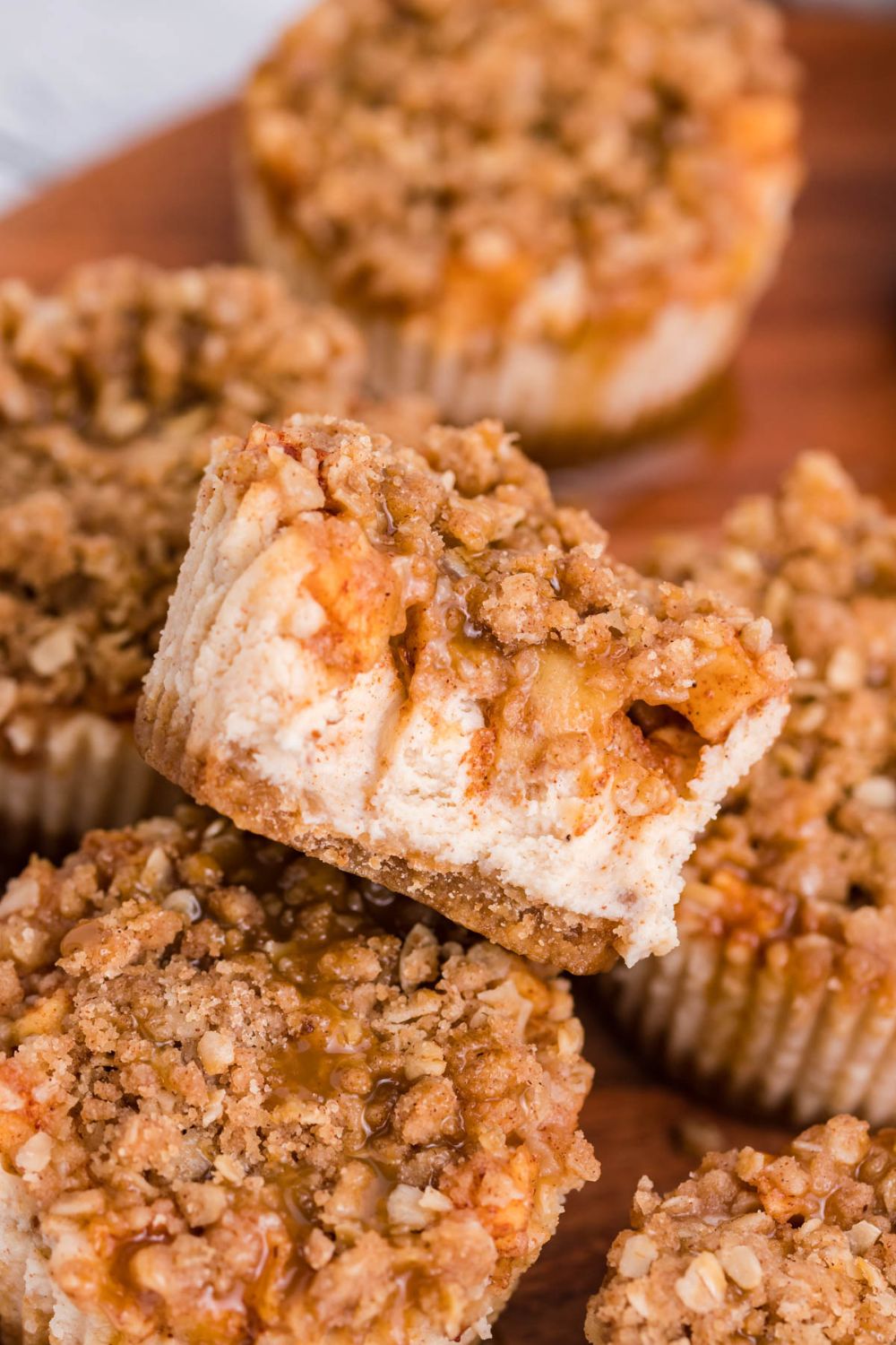 marble counter with a wooden cutting board on table with Apple Crisp Cheesecake Bites scattered on the board 