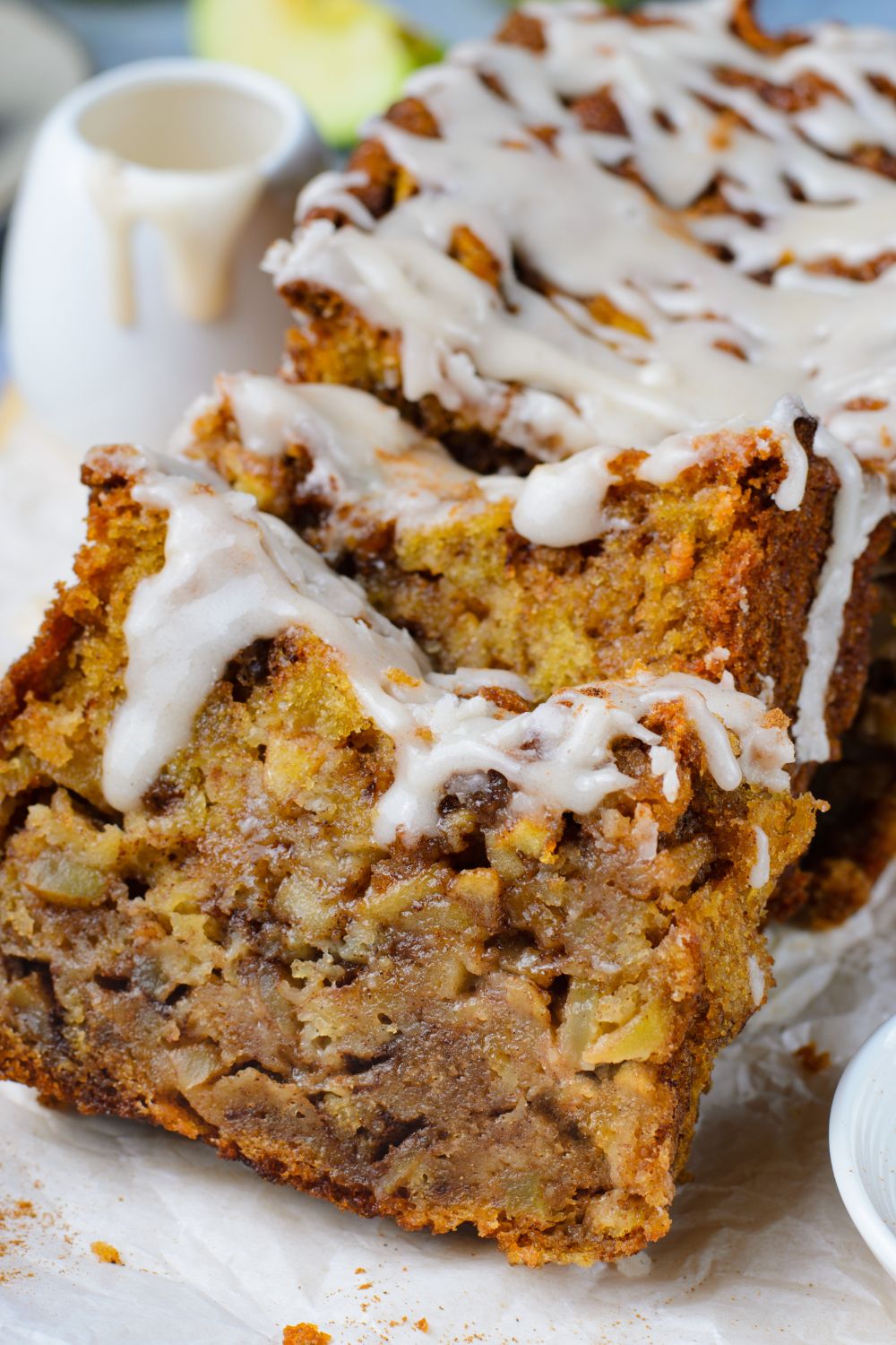 Amish Apple Fritter Bread sliced and placed on table with a cup with the glaze in it as well 