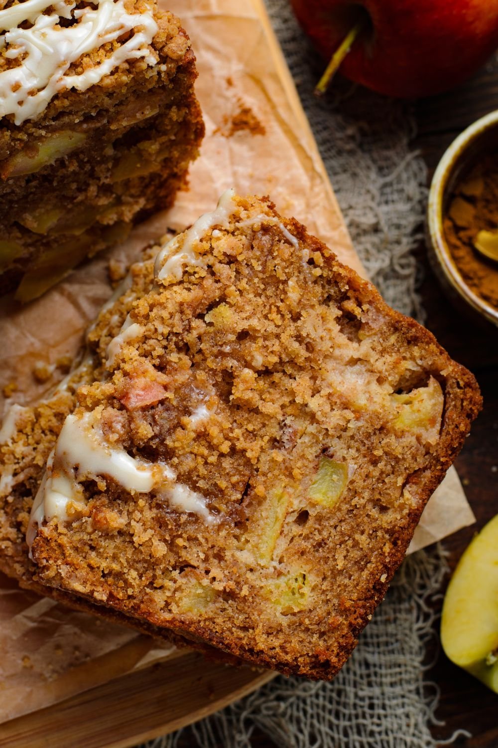 spatula on table with a slice of Apple Cinnamon Loaf Cake on it and a small bowl of cinnamon off to the side 