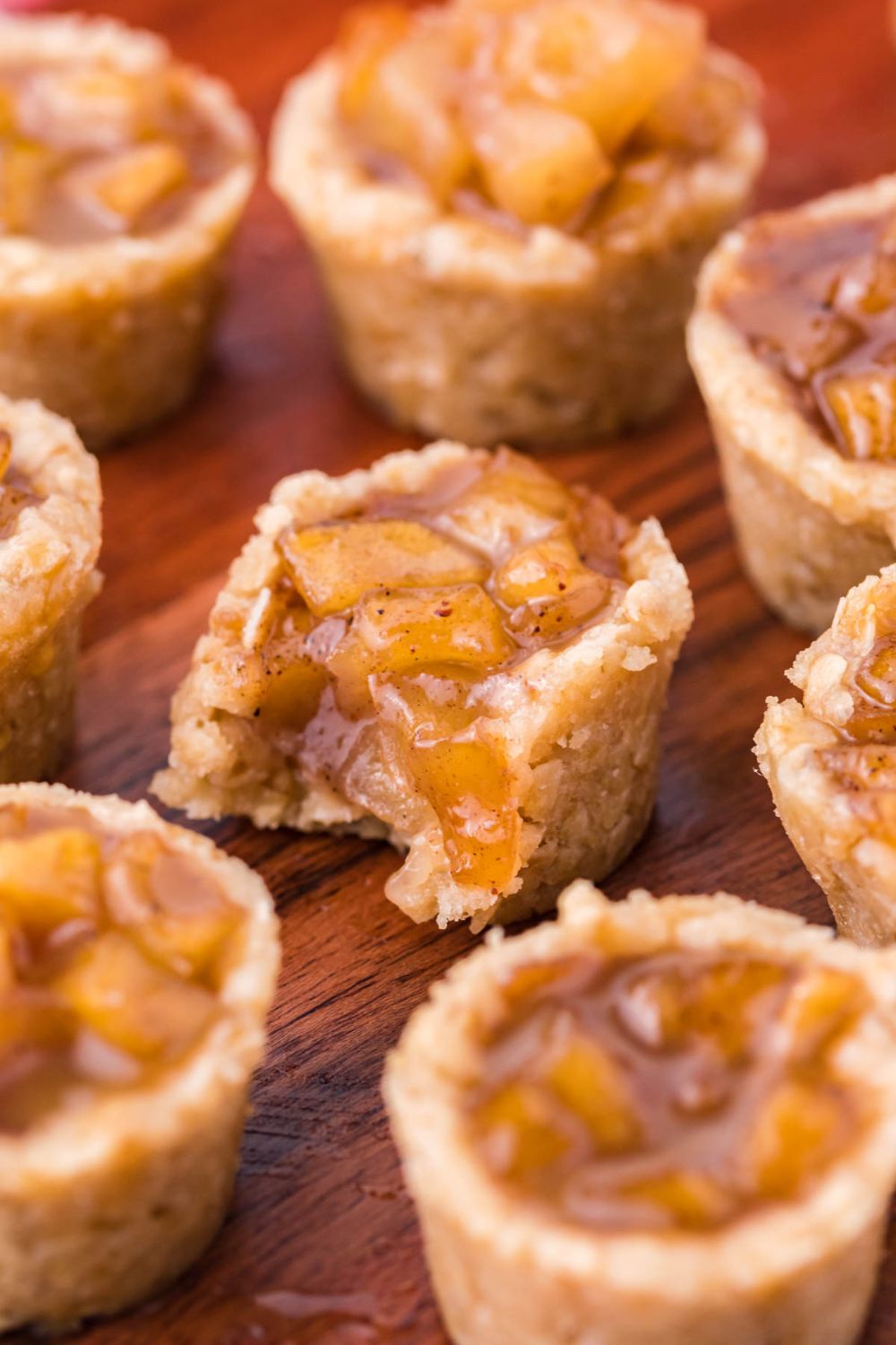 Mini Apple Crisp Bites placed around the table and one in center with a bite taken out of it 