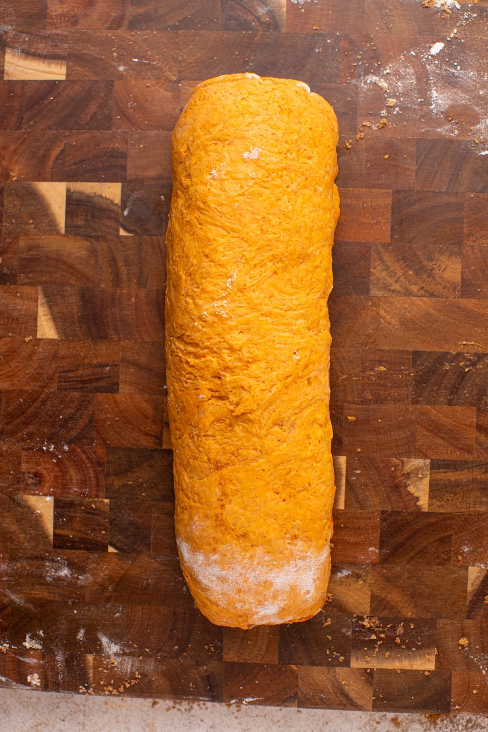 rolled Pumpkin Cinnamon Roll dough on wooden cutting board 