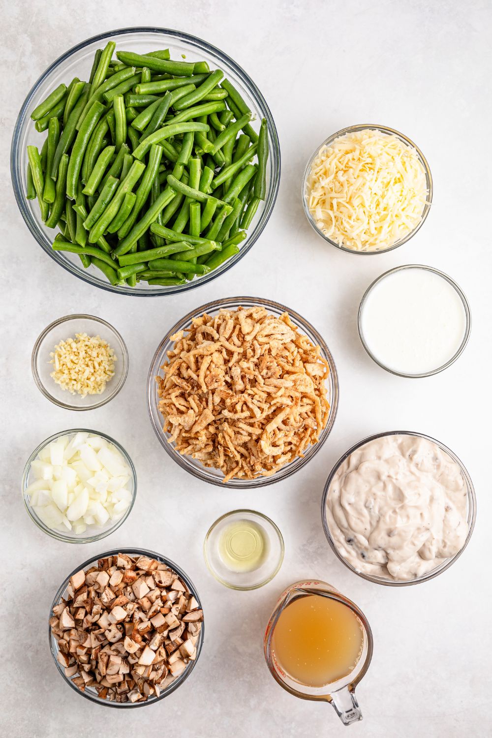 Green Bean Casserole ingredients in single serve bowls on table - green beans, garlic, onion, crispy fried onions, and more