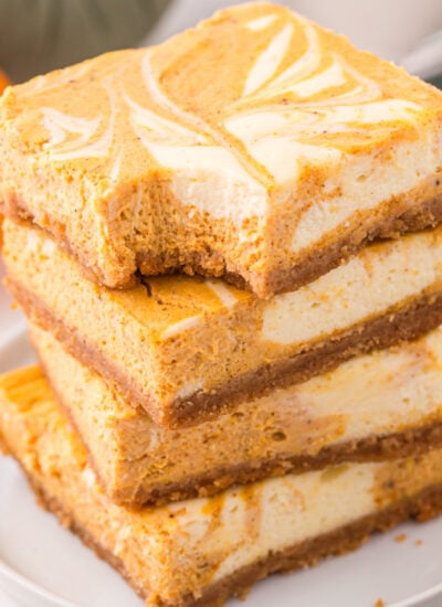 Sliced Swirled Pumpkin Cheesecake Bars stacked on a whit platw