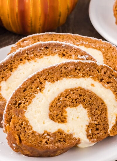 Pumpkin Roll Cake sliced on a white plate sprinkled with powdered sugar
