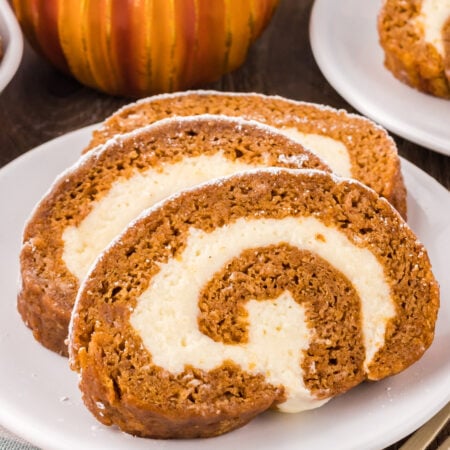 Pumpkin Roll Cake sliced on a white plate sprinkled with powdered sugar