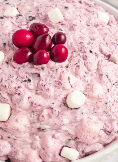Cranberry Fluff Salad in a large white serving bowl topped with fresh cranberries and mini marshmallows