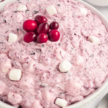 Cranberry Fluff Salad in a large white serving bowl topped with fresh cranberries and mini marshmallows