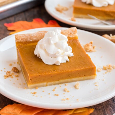 Sheet Pan Pumpkin Pie slice on a white plate on a dark wood table