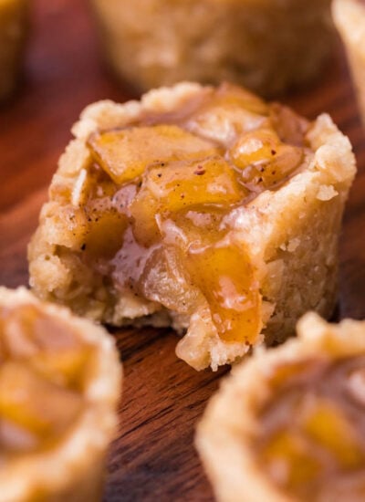 Mini Apple Crisp Bites on a dark wood table with a bite missing from the one in the center