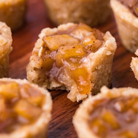 Mini Apple Crisp Bites on a dark wood table with a bite missing from the one in the center
