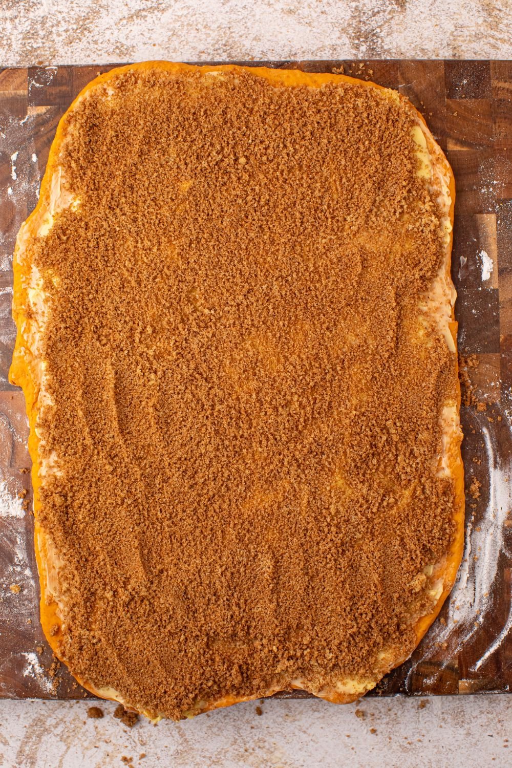 rolled out pumpkin cinnamon roll dough with cinnamon and sugar mixture spread over the top of it 
