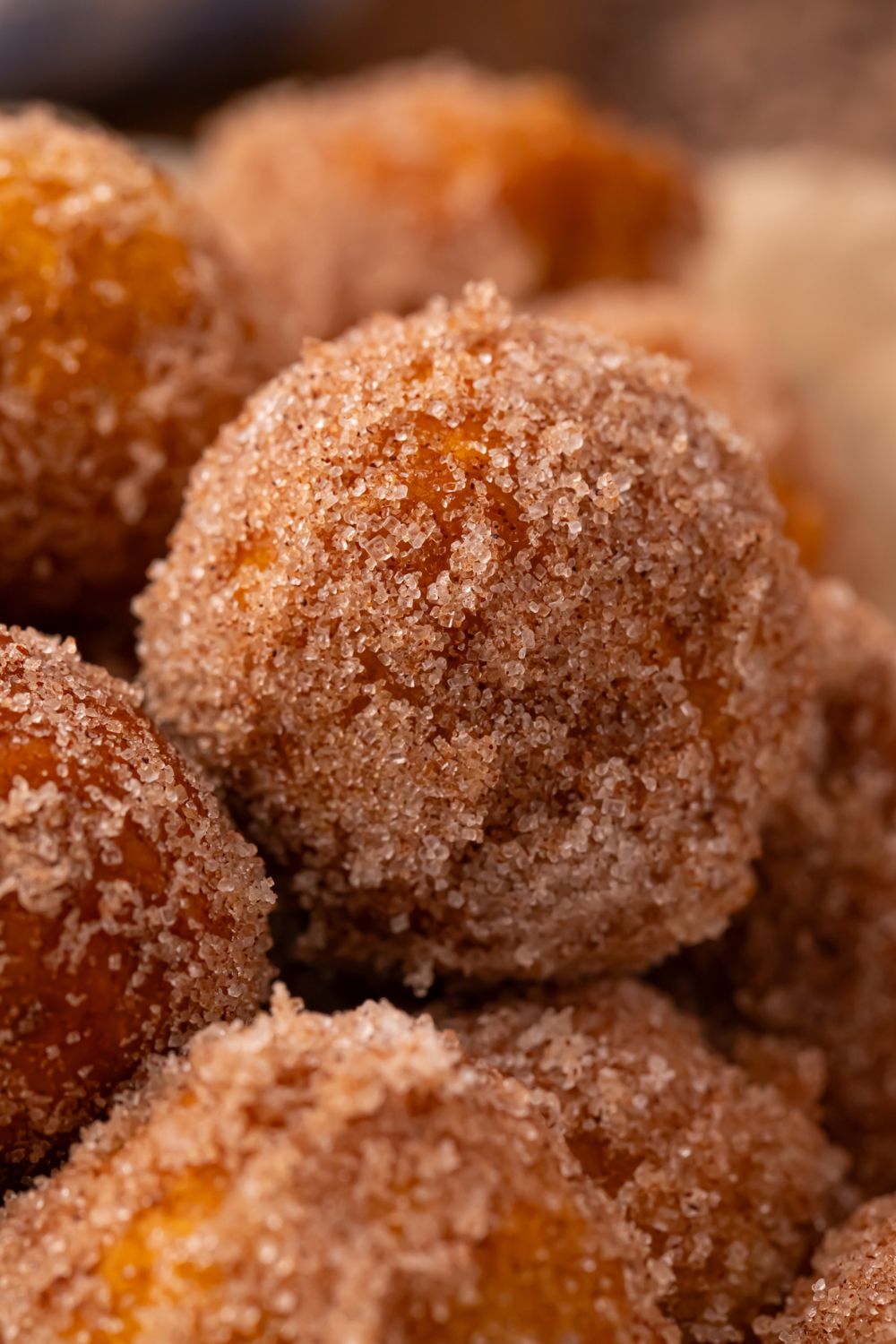 close up look of round Pumpkin Pie Donut Holes that are rolled into cinnamon sugar coating 