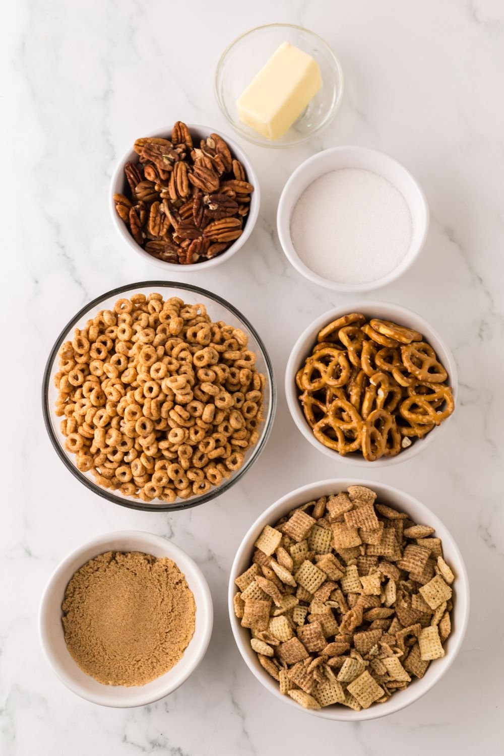 Pumpkin Spice Chex Mix ingredients all in single serve bowls sitting on a marble counter 