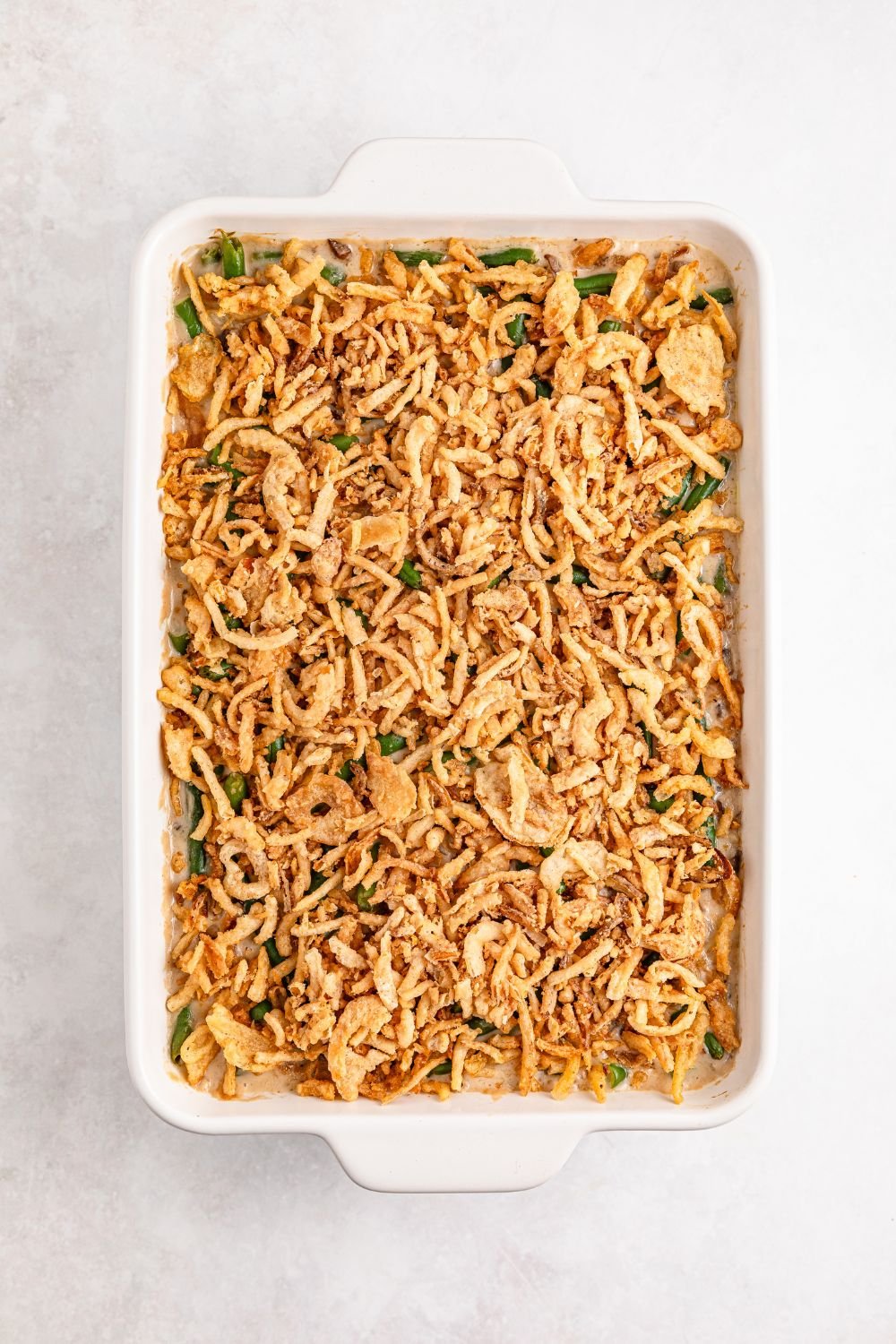 uncooked Green Bean Casserole in a white casserole dish on table 