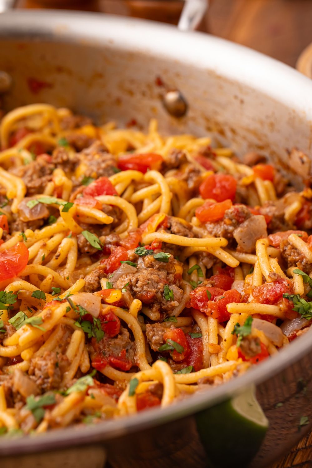 a metal skillet with Cheesy Taco Spaghetti topped with fresh parsley on top 