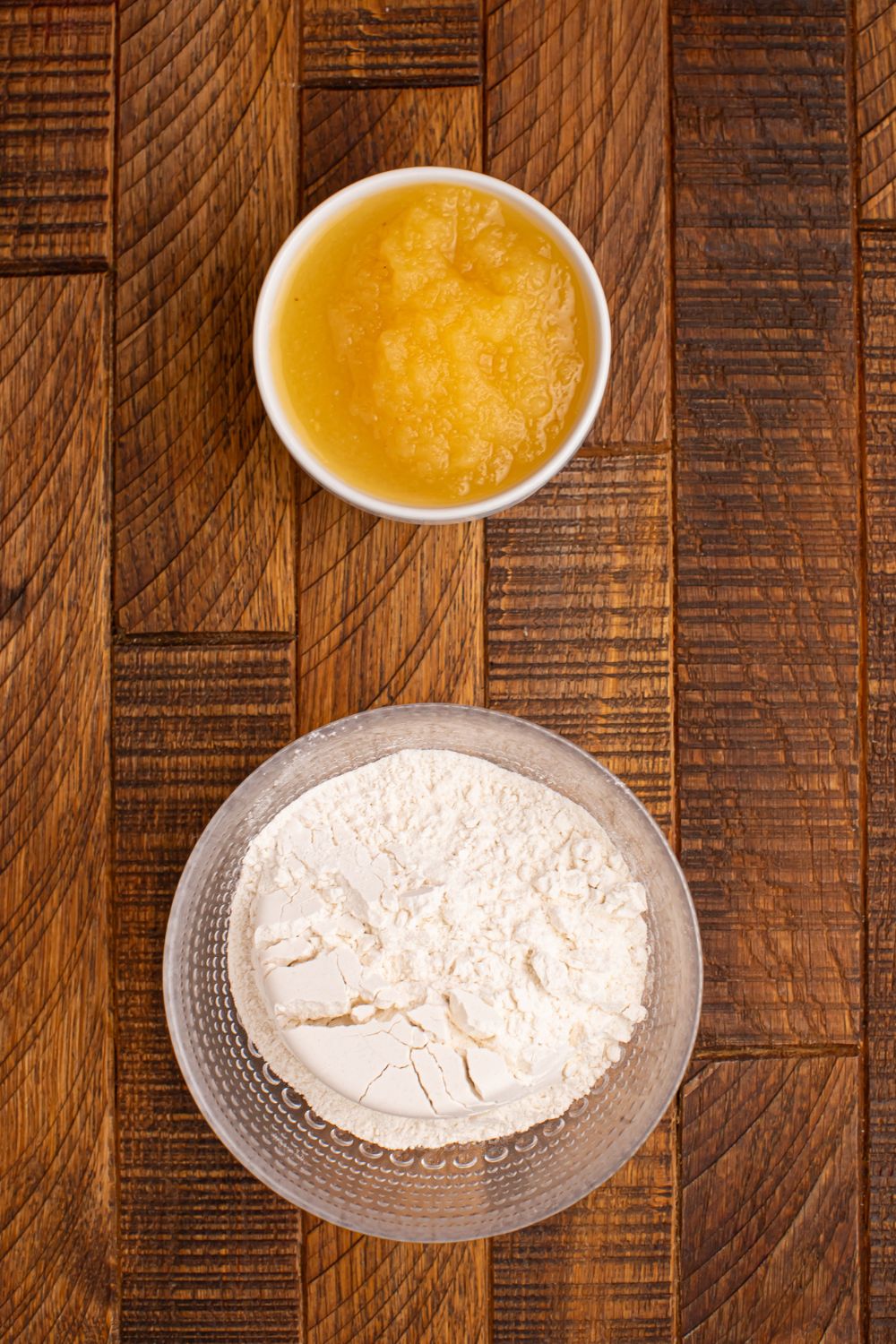 glass bowl of self rising flour and applesauce in a bowl on wooden table 