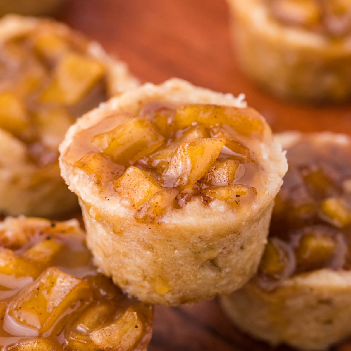 Mini Apple Crisp Bites placed around a wooden table with one stacked on top of another one 