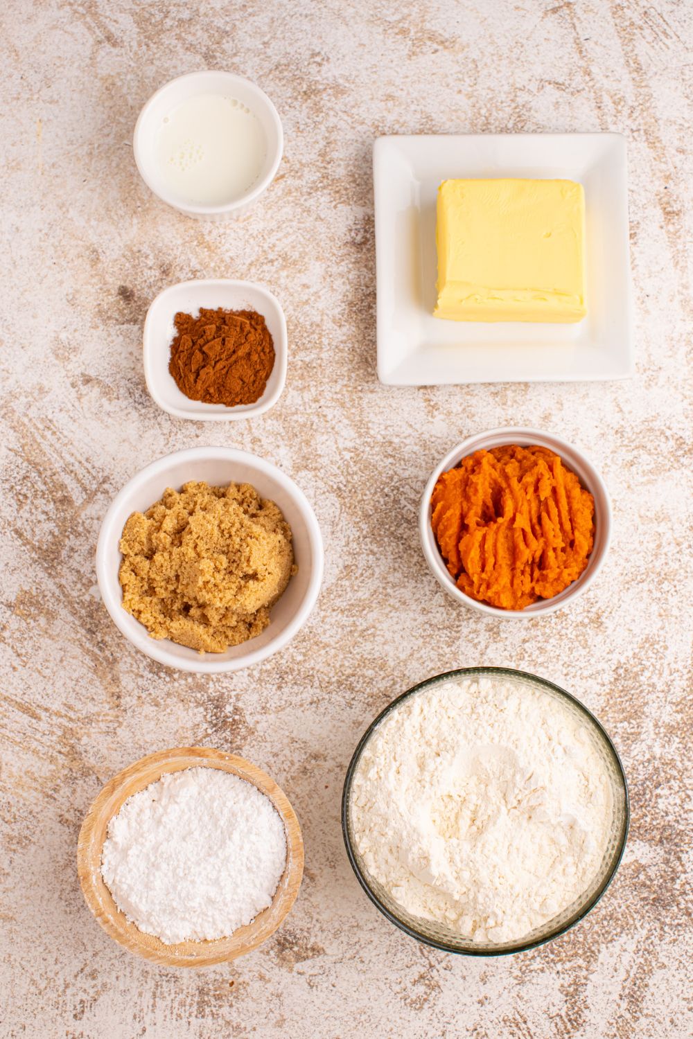 all the ingredients to make Pumpkin Cinnamon Rolls in small containers on table