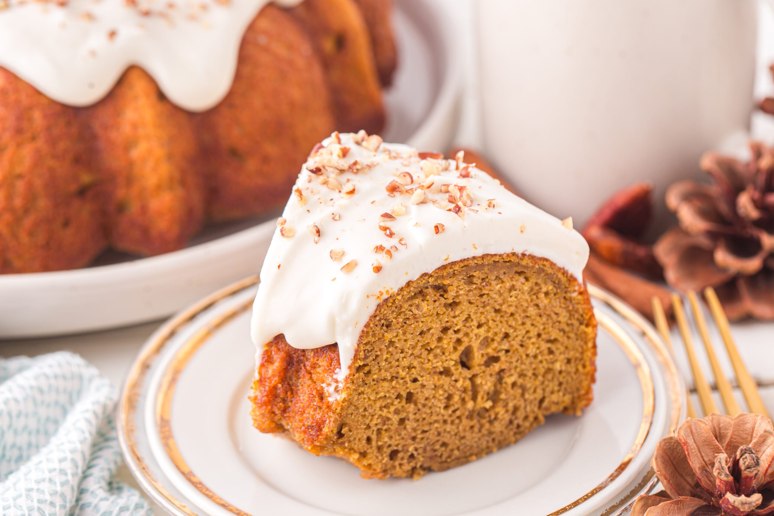 Slice of the Pumpkin Bundt Cake on a white serving plate topped with nuts 