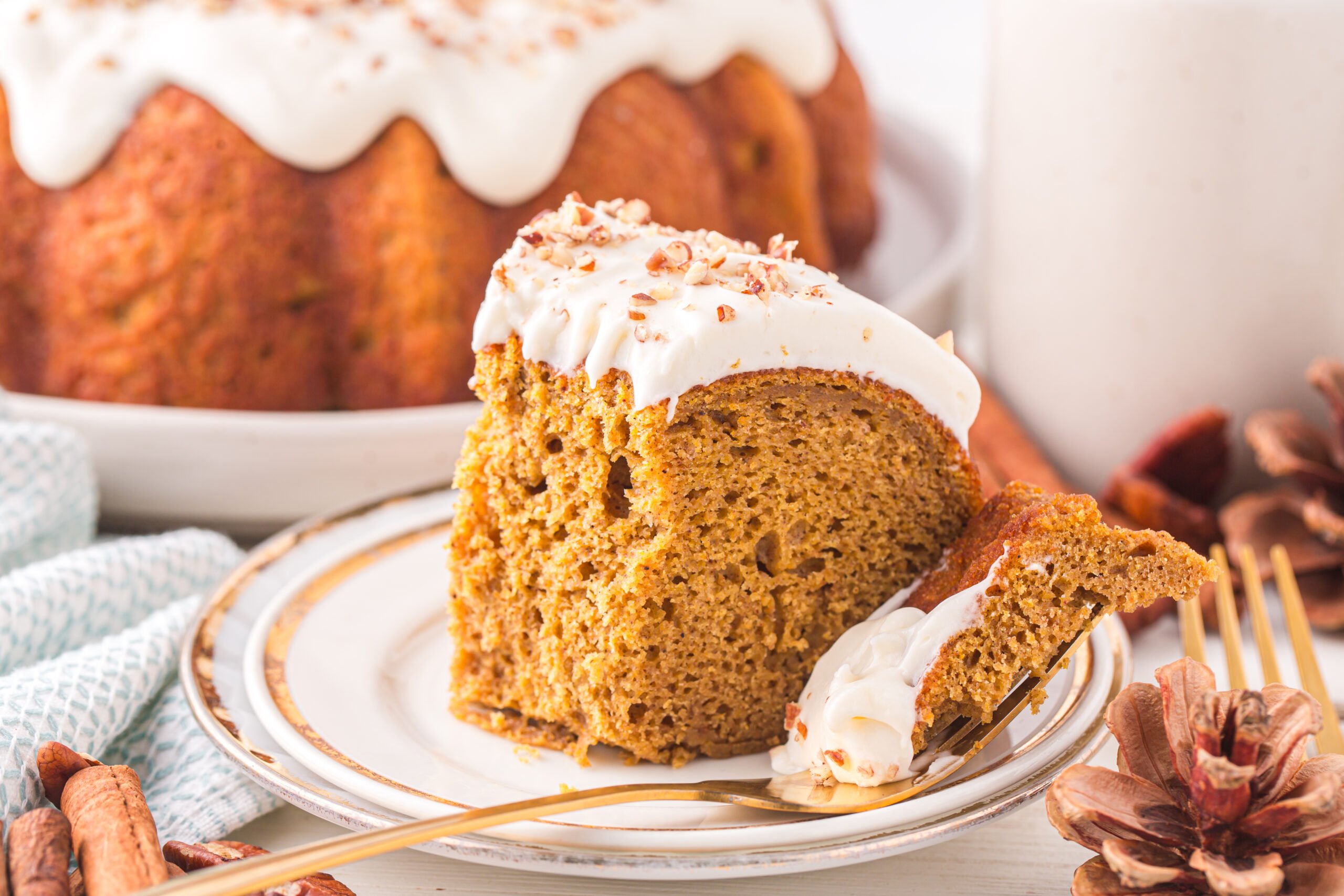 Slice of the Pumpkin Bundt Cake on a white serving plate with a fork holding a bite 