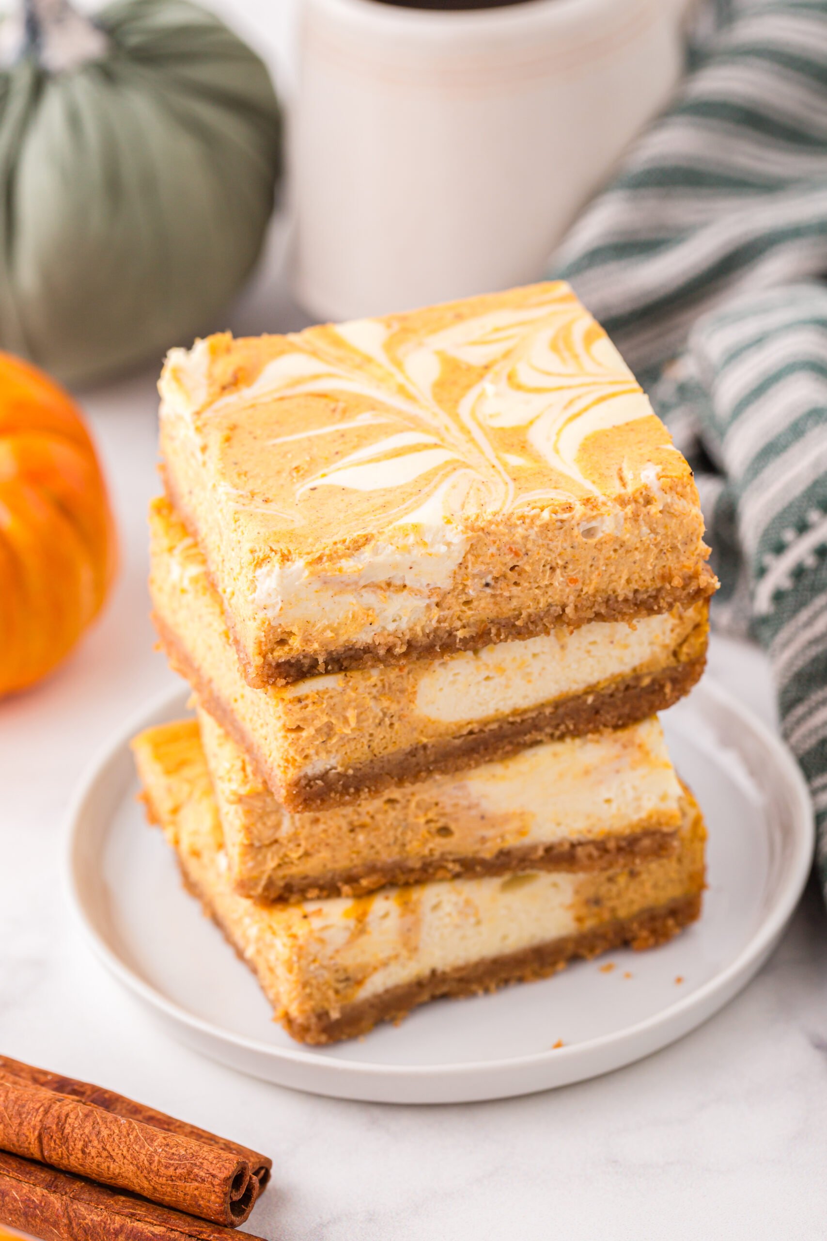 Stacked Swirled Pumpkin Cheesecake Bars on a white serving plate