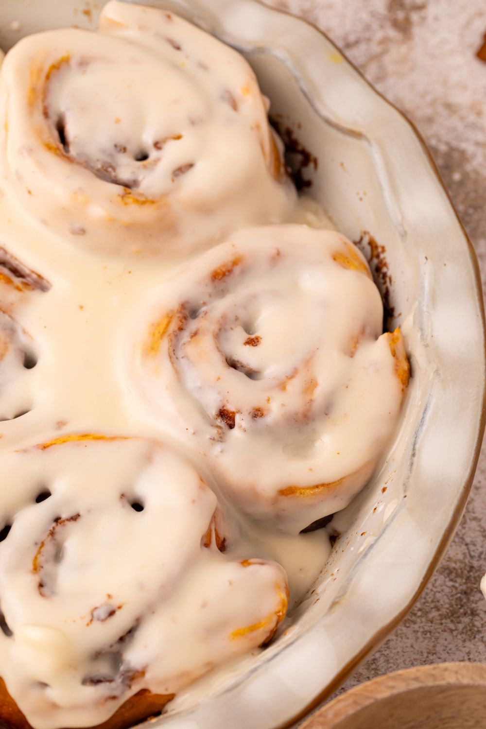 Pumpkin Cinnamon Rolls in a pie plate dish on table with a glaze drizzled over the top of the rolls