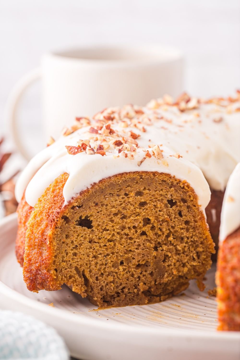 side view of a Pumpkin Bundt Cake on a cake platter with some of the cake cut out of it 