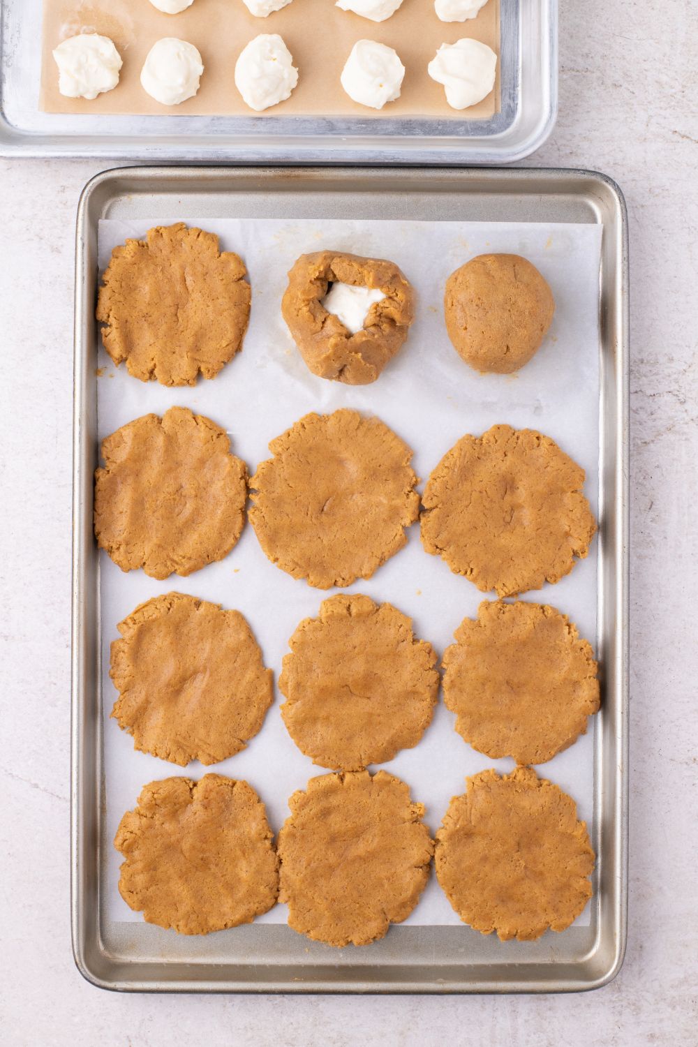 cheesecake filling in center of one cookie on a baking sheet on table