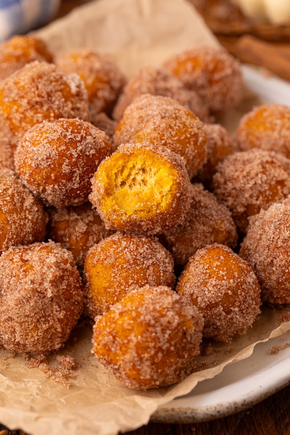 white plate with parchment paper that is full of Pumpkin Pie Donut Holes rolled in cinnamon and sugar 