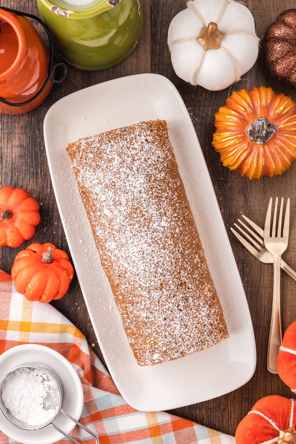 Pumpkin Cake Roll on a long platter sitting on a rustic wooden table with forks to side