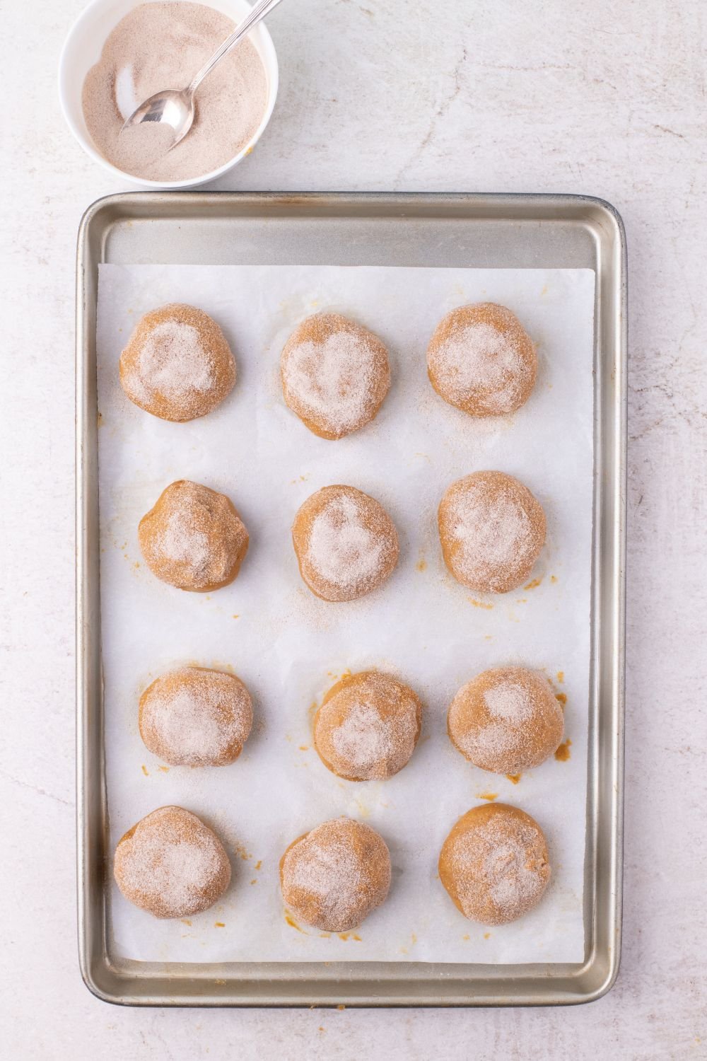 cinnamon sugar coated pumpkin cheesecake stuffed cookies on a baking tray 